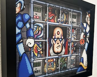 May include: A framed 3D pixel art piece featuring characters from the Mega Man X video game series. The artwork is encased in a black frame and includes the artist's signature and the text "FANBIT CREATIONS". The characters are in a grid-like layout.