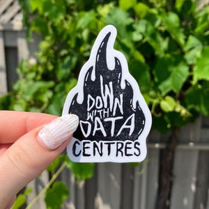 May include: A die-cut sticker featuring a black flame graphic with a white border. The text "DOWN WITH DATA CENTRES" is printed in a bold, hand-drawn style font across the centre of the flame shape, creating a high-contrast black and white design.