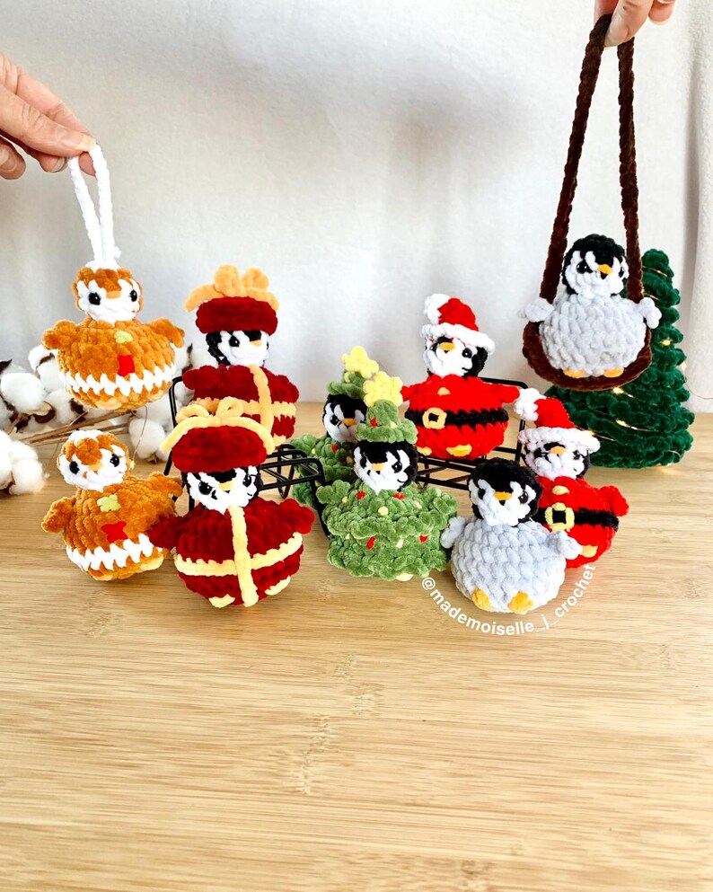 No sew crochet patterns of penguins with theme of Christmas. Showing them together, with one showing a car hanger penguin and one Christmas ornament penguin. By Mademoiselle J Crochet