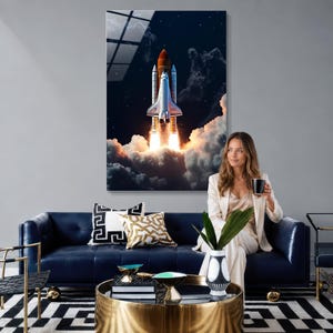 May include: A vertical wall art print depicting a space shuttle launching into a dark night sky, surrounded by thick white clouds and bright orange exhaust flames. The shuttle features a white body with a large orange external fuel tank.