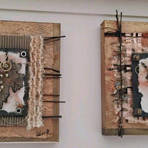 Könnte beinhalten: Zwei quadratische Mixed-Media-Kunstwerke. Jedes zeigt einen strukturierten Hintergrund mit einem zentralen Quadrat, das ein Metallblatt-Design enthält. Eines hat ein gewebtes Stoffelement, das andere ein gewebtes Bandelement. Beide haben Metalldrahtakzente.
