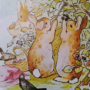 May include: A watercolor illustration featuring three light brown rabbits with white tails. Two rabbits stand on their hind legs reaching for dark berries on a leafy branch, while a third rabbit sits nearby. A woven basket and two small birds are present.