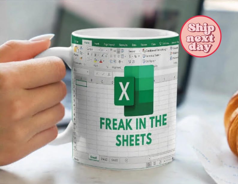 K&ouml;nnte beinhalten: Eine wei&szlig;e Keramiktasse mit einem gr&uuml;nen und wei&szlig;en Microsoft Excel-Tabellenblattdesign. Die Tasse zeigt das Excel-Logo und den Text "Freak in the Sheets".