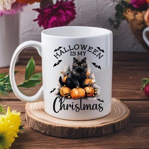 Puede incluir: Taza de cer&aacute;mica blanca con un gato negro sentado sobre una pila de calabazas. La taza tiene el texto "Halloween is my Christmas" impreso en ella.