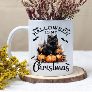 Puede incluir: Taza de cer&aacute;mica blanca con un gato negro sentado sobre calabazas. La taza tiene el texto "Halloween is my Christmas" impreso en ella.