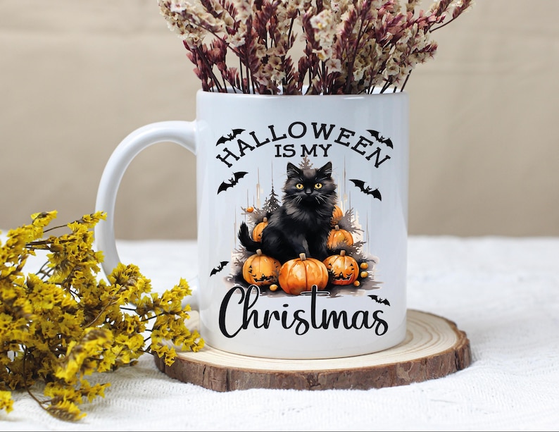 Puede incluir: Taza de cer&aacute;mica blanca con un gato negro sentado sobre calabazas. La taza tiene el texto "Halloween is my Christmas" impreso en ella.