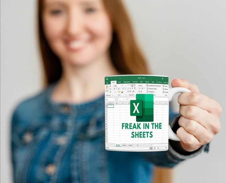 K&ouml;nnte beinhalten: Eine wei&szlig;e Kaffeetasse mit einem gr&uuml;nen und wei&szlig;en Microsoft Excel-Tabellenblatt-Design. Der Text "Freak in the Sheets" ist auf die Tasse gedruckt.
