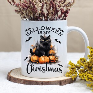 Puede incluir: Taza de cer&aacute;mica blanca con un gato negro sentado sobre una pila de calabazas. La taza tiene el texto "Halloween is my Christmas" impreso en ella.