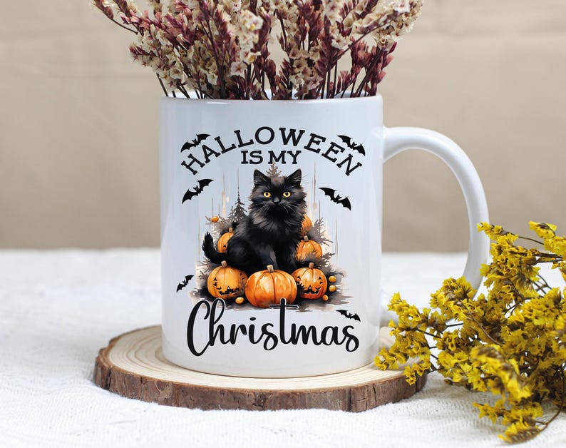 Puede incluir: Taza de cer&aacute;mica blanca con un gato negro sentado sobre una pila de calabazas. La taza tiene el texto "Halloween is my Christmas" impreso en ella.