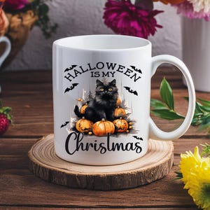 Puede incluir: Taza de cer&aacute;mica blanca con un gato negro sentado sobre una pila de calabazas naranjas. La taza tiene el texto "Halloween is my Christmas" impreso en ella.
