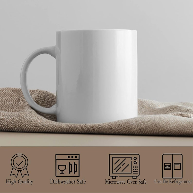 Puede incluir: Una taza de cer&aacute;mica blanca con un asa curva, apoyada sobre una tela beige. La taza es lisa y suave, con un acabado brillante. La imagen tambi&eacute;n incluye iconos que indican que la taza es de alta calidad, apta para lavavajillas, apta para microondas y refrigerable.