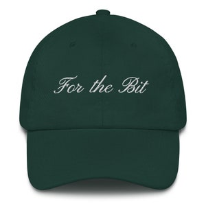 Può includere: Un cappellino da baseball verde scuro con visiera curva. La frase "For the Bit" è ricamata in bianco sulla parte anteriore. Il cappellino è realizzato in un tessuto morbido e ha una corona strutturata.