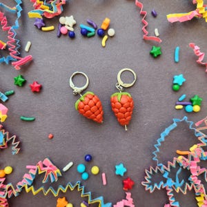 May include: A pair of silver earrings with red and green polymer clay strawberry charms.