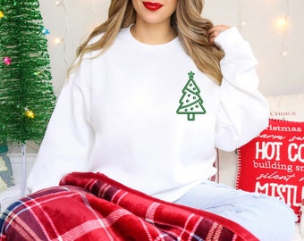 May include: White sweatshirt featuring a green Christmas tree design on the front. The tree has a star on top and decorative dots. The sweatshirt is part of a holiday-themed collection.