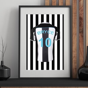 Peut inclure: Impression encadr&eacute;e d'un maillot de football &agrave; rayures noires et blanches avec le nom "BRYCE" et le num&eacute;ro "10" en bleu clair. Le maillot est centr&eacute; sur un fond &agrave; rayures noires et blanches.