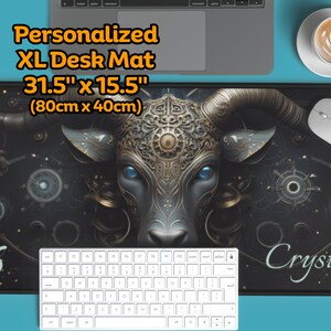 Può includere: Un tappetino da scrivania XL nero e oro con un'illustrazione dettagliata di una testa di toro. Il tappetino misura 80 cm x 40 cm (31,5 pollici x 15,5 pollici) e presenta il testo "Personalized XL Desk Mat" e "Crystal".