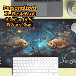 Può includere: Un tappetino da scrivania XL personalizzato con un design blu e oro che presenta due pesci, un quadrante dell'orologio e stelle. Il tappetino misura 80 cm x 40 cm e ha il nome "Suzanna" stampato su di esso.