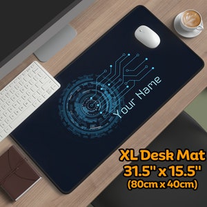 Op de afbeelding: Een blauwe en zwarte XL-bureau mat met een print van een circuitbord en de tekst "Your Name". De mat meet 80 cm x 40 cm.