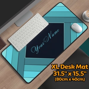 May include: A teal and blue geometric design XL desk mat with a black rectangle in the center that says "Your Name". The mat measures 31.5 inches by 15.5 inches (80cm x 40cm).