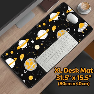 May include: A black and yellow XL desk mat with a space theme. The mat features flying saucers, planets, and stars. The mat is 31.5 inches by 15.5 inches (80cm x 40cm).