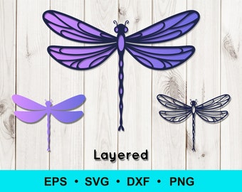 May include: Three layered digital cut files of a dragonfly in purple, blue, and black. The files are labeled "Layered" and include the file types EPS, SVG, DXF, and PNG.