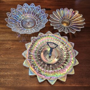 May include: Three iridescent glass serving dishes in a sunflower design. The largest dish has a metal handle in the centre.