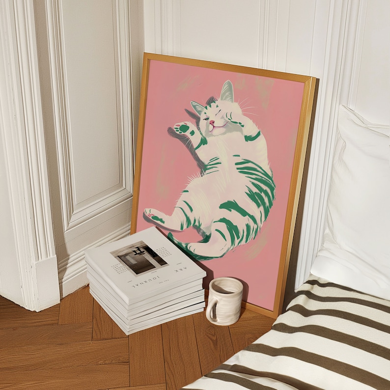 May include: A framed illustration of a white cat with green stripes lying on its back on a pink background.