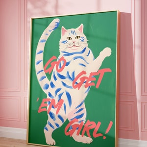 May include: A green canvas print with a white cat with blue stripes standing on its hind legs. The cat has a pink nose and a pink tongue. The text "GO GET 'EM GIRL!" is written in pink on the canvas.