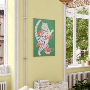 May include: A green canvas print featuring a white cat with blue stripes standing on its hind legs. The cat is looking to the right and the text "Go Get 'Em Girl!" is written in pink on the canvas.