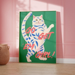 May include: A green poster with a white cat with blue stripes standing on its hind legs. The cat has a pink nose and pink paw pads. The text on the poster says "Go Get 'Em Girl!"
