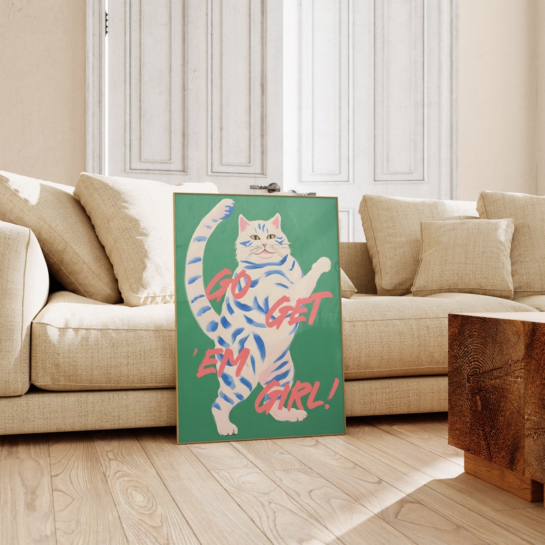 May include: A green poster with a white cat with blue stripes standing on its hind legs. The cat has a pink nose and a pink mouth. The text on the poster says "Go Get 'Em Girl!"