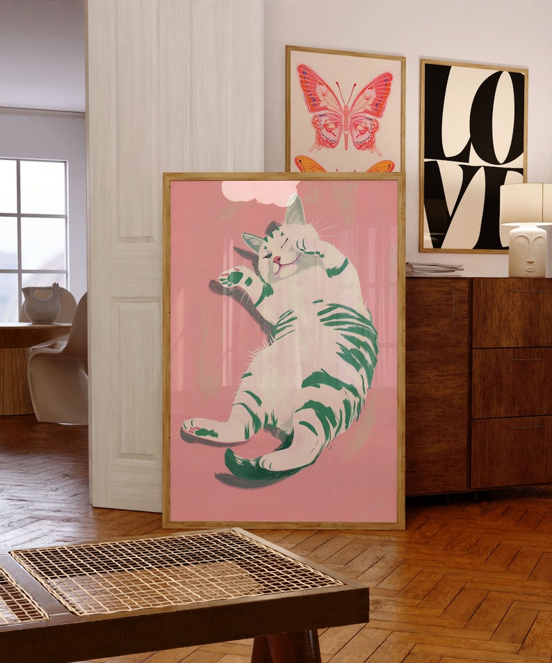 May include: A framed illustration of a white cat with green stripes, lying on its back with its paws in the air, on a pink background.