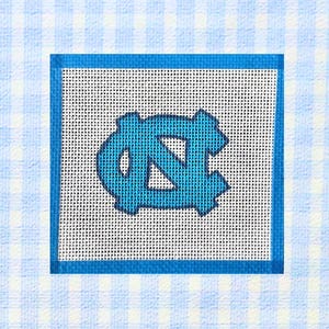 Könnte beinhalten: Eine quadratische Gobelin-Leinwand mit dem Logo der University of North Carolina in Carolina-Blau. Das Logo befindet sich auf einem weißen Netz-Hintergrund, der von einem blauen Rand umgeben ist. Der Hintergrund ist ein hellblaues und weißes Vichy-Muster.