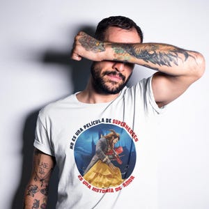 Op de afbeelding: Wit T-shirt met een ronde afbeelding met een sc&egrave;ne uit de film Beauty and the Beast. De tekst rond de afbeelding luidt "No es una pel&iacute;cula de superheroes es una historia de amor".