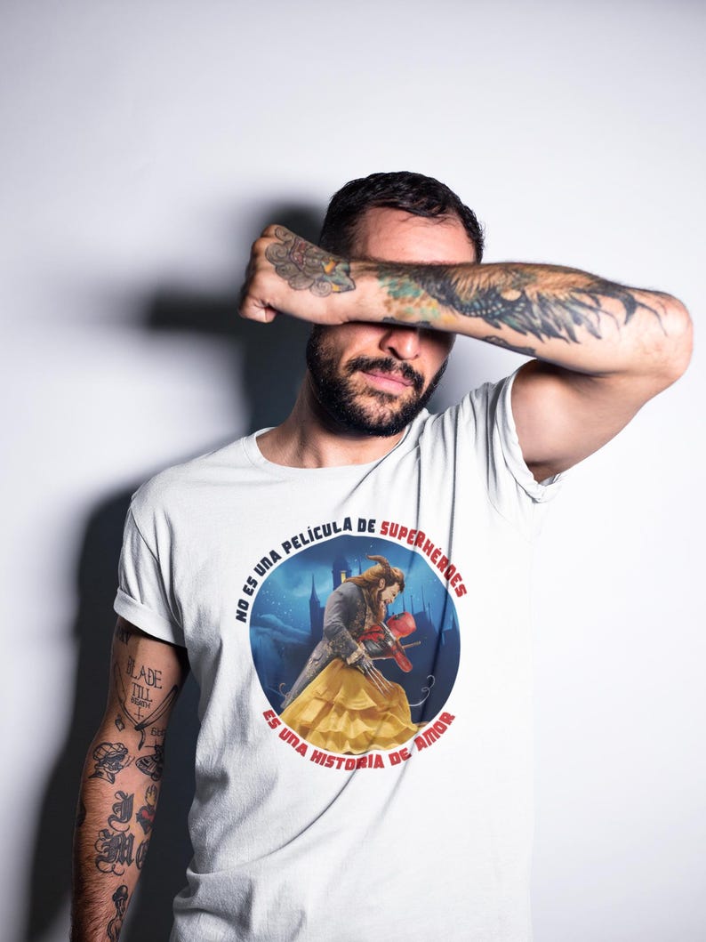 Op de afbeelding: Wit T-shirt met een ronde afbeelding met een sc&egrave;ne uit de film Beauty and the Beast. De tekst rond de afbeelding luidt "No es una pel&iacute;cula de superheroes es una historia de amor".
