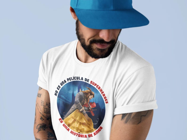 Op de afbeelding: Een wit T-shirt met een ronde afbeelding van een sc&egrave;ne uit de film Belle en het Beest. De afbeelding bevat Spaanse tekst die luidt "No es una pel&iacute;cula de superh&eacute;roes. Es una historia de amor."