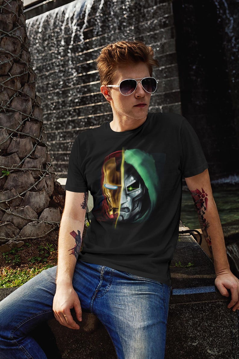 May include: A black t-shirt with a graphic of Iron Man and Doctor Doom's faces, split down the middle. The graphic is in red, yellow, green, and silver.
