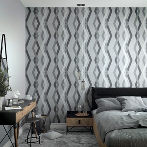 Puede incluir: Un dormitorio con papel tapiz de patrón geométrico gris y blanco, una cama con ropa de cama gris, una mesita de noche negra y un escritorio negro con un espejo.