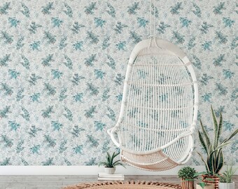 May include: A white wicker hanging chair with a blue and white floral patterned wallpaper background. The chair is hanging from the ceiling and there are plants in pots on the floor.