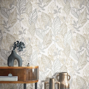 May include: A white wallpaper with a gray and beige leaf pattern. The wallpaper is shown in a room with a wooden console table, two vases, and a decorative sculpture.