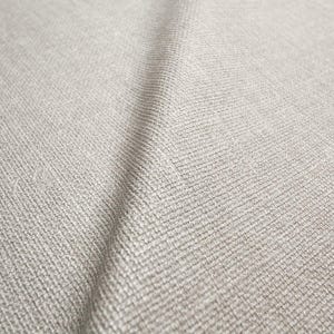 May include: Close-up of a textured, light grey fabric. The weave is visible, creating a subtle pattern. The fabric has a soft, neutral tone, suitable for various textile applications.