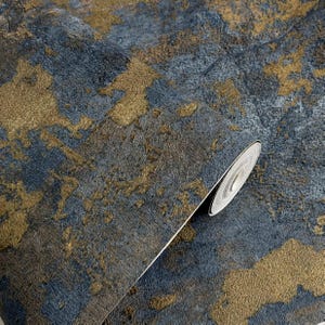 May include: A roll of wallpaper featuring a textured surface with an abstract pattern of deep navy blue and metallic gold. The design displays irregular, organic shapes that resemble weathered stone or oxidized metal with a matte finish.