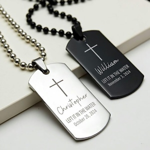 May include: Two silver dog tag necklaces with crosses engraved on them. The top tag reads "William LEFT IT IN THE WATER November 3, 2024". The bottom tag reads "Christopher LEFT IT IN THE WATER October 20, 2024".