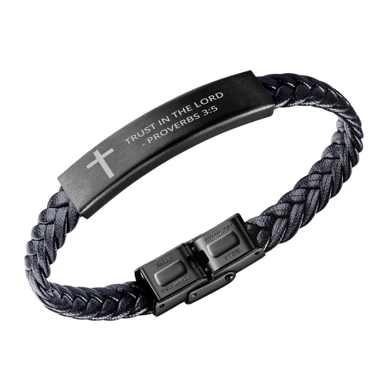 May include: Black leather bracelet with a black metal clasp and a black metal plate with the inscription "TRUST IN THE LORD - PROVERBS 3:5" and a cross.