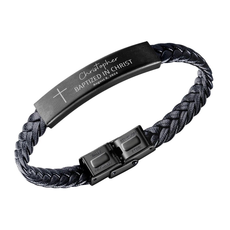 K&ouml;nnte beinhalten: Schwarzes Lederarmband mit einer schwarzen Metallplatte, die mit dem Text "Christopher Baptized in Christ August 8, 2024" graviert ist. Die Platte hat ein kleines Kreuz, das darauf graviert ist. Das Armband hat einen schwarzen Metallverschluss.