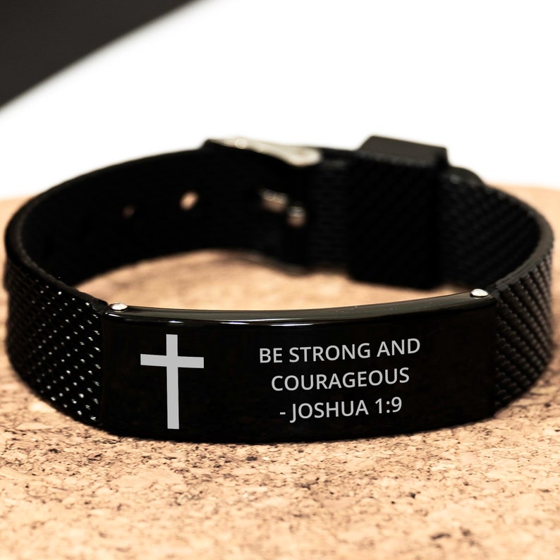 May include: Black silicone bracelet with a silver metal plate engraved with a cross and the words "Be strong and courageous - Joshua 1:9".