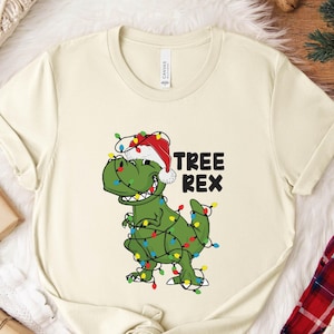a white t - shirt with a green dinosaur wearing a santa hat
