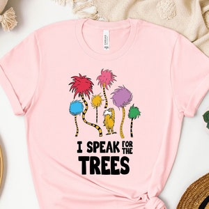 May include: Pink t-shirt featuring a graphic of the Lorax and the Truffula Trees. The text "I speak for the trees" is printed on the shirt.