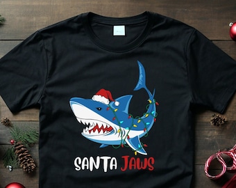 May include: Black t-shirt with a cartoon shark wearing a Santa hat and Christmas lights. The text "SANTA JAWS" is printed below the shark.