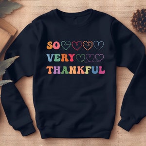 May include: A black sweatshirt with the text "SO VERY THANKFUL" in rainbow colors with hearts between the words.